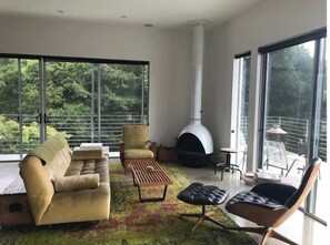Relax in a spacious living area with a comfortable sofa and armchair, surrounded by lush greenery views.