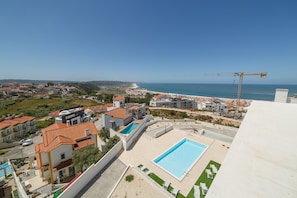 Nazaré Views X is a brand new holiday apartment in the centre of Nazaré, on Portugal's Silver Coast, with an outdoor swimming pool and a modern décor. It can accommodate up to 4 people. 

The apartment has fabulous views over the village and beach of Nazaré, and a large balcony with outdoor furniture where you can relax and sunbathe.

One of the bedrooms is en-suite, with a double bed and a private bathroom. The second bedroom has two single beds. Both bathrooms have showers.

On the rooftop, you also have access to a private terrace with panoramic views over Nazaré, where you can enjoy the sunset or relax after a day at the beach.

Outside, you have access to a huge shared pool, where you can also unwind away from the hustle and bustle of the busy downtown area of Nazaré.

Other amenities include: 
- Free Wi-fi 
- Fully equipped kitchen
- Satellite TV
- Air conditioning
- Dishwasher
- Washing Machine
- Coffee Machine
- Parking space for 1 vehicle in the underground garage

Towel change/cleaning service is also available during your stay, at an extra charge.

This fantastic holiday apartment is just 2 km from Nazaré beach and very close to supermarkets, cafés and restaurants. The village's Pingo Doce supermarket is 500 metres away.

There are many reasons to visit this fishing village all year round! Among the main tourist attractions, don't miss the famous Nazaré beach and the typical fishing boats and dried fish sellers on the sand. On the waterfront, you will find several restaurants, cafés and shops.

Nazaré — well known for its traditions connected to the sea — is also the home of several events and tourist attractions, such as the Sanctuary of Our Lady of Nazaré, São Miguel Fort or the lift that connects Nazaré to Sítio, among many others. Between October and March, the giant waves of the North Canyon are another attraction not to be missed. 

Contact us for more information or to book your holiday in Nazaré! - Nazaré Views X - T2 Holiday Apartment with views of Nazaré By SCH (Nazaré)