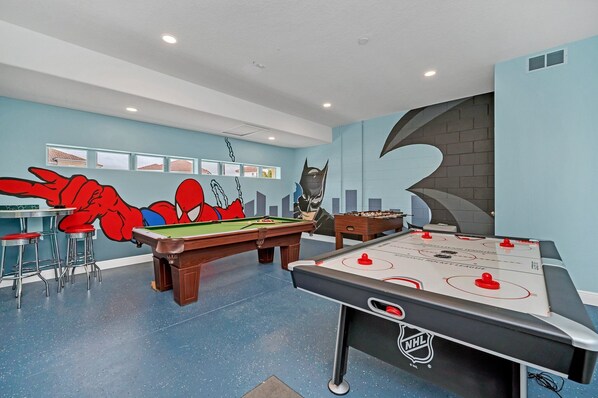 Espaço de lazer com mesa de bilhar, mesa de futebol de botão e banquetas de bar.
