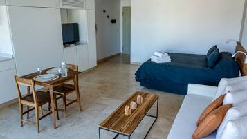 Una habitación de hotel moderna con cama, sofá, mesa de madera y televisor.