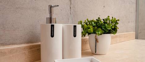 A bathroom with a white sink, a potted plant, and a soap dispenser.