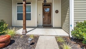 Une maison avec un porche à l’avant, une porte en bois et une boîte aux lettres.