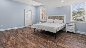 Une chambre à coucher avec un lit, une table de chevet, une porte et une fenêtre.