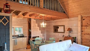 Een gezellig cabin interieur met een eethoek, een bank en een trap naar een hoger gelegen verdieping.