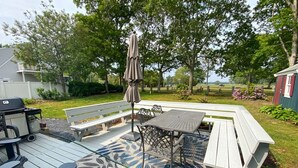Un patio con mesa y sillas, una parrilla y una terraza de madera.