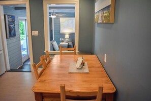 Un comedor con una mesa y sillas de madera, un ventilador de techo y un cuadro en la pared.