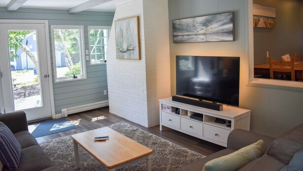 Una sala de estar con televisor, sofá y mesa de centro.