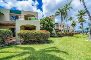 A resort with multiple-story buildings, palm trees, and well-maintained lawns.