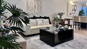 Un salon moderne avec un canapé blanc, une table basse noire et une décoration murale en macramé.