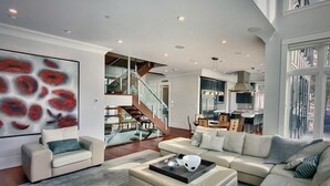 A spacious living room with a large sofa, a coffee table, and a staircase leading to an upper level. - RMR: Luxury Ski-in/out Mountain-side 4 Bedroom Home (Sleeps 10).  (Revelstoke)