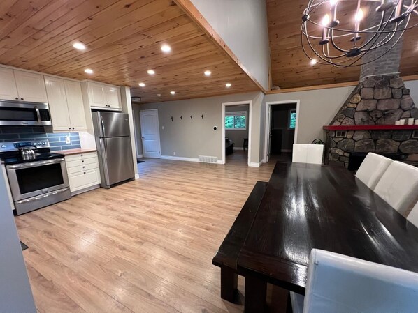 A modern kitchen with stainless steel appliances, a wooden ceiling, and a stone fireplace. - Beautiful on the Water Year Round Cottage Awaits (Combermere)