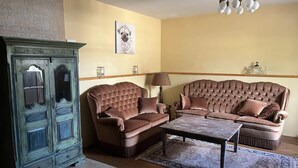 Una sala de estar con un sofá marrón, una mesa de centro de madera y un aparador antiguo.