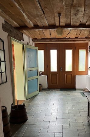 Enter a cozy space with a rustic ceiling and tiled floor, featuring two doors with frosted glass panels.