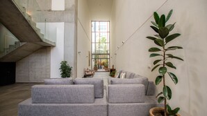 Una sala de estar moderna con un sofá modular, una planta en maceta y una escalera.