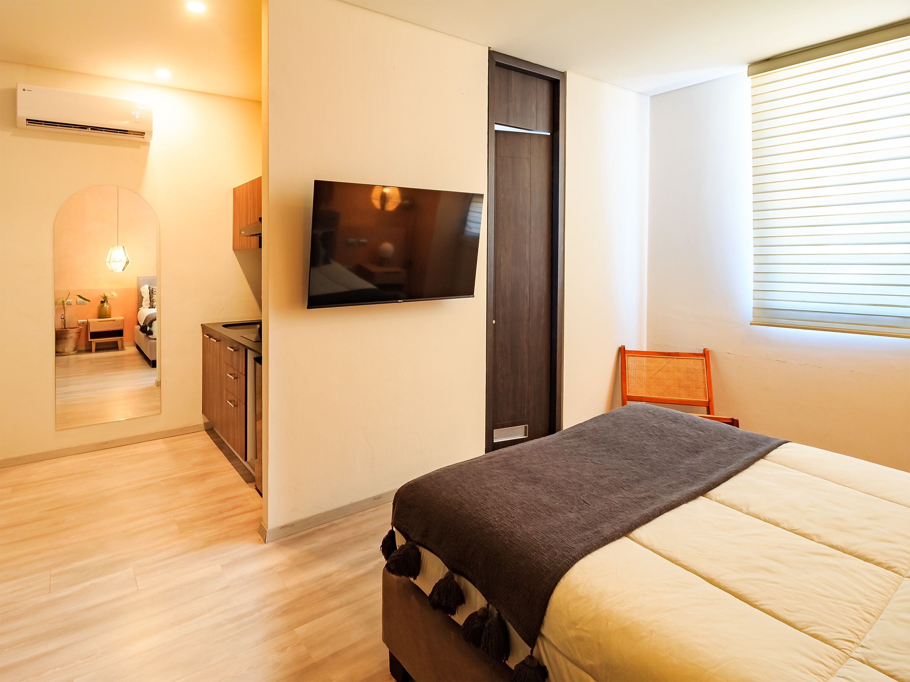 Un dormitorio con cama, televisor, armario y ventana con persianas.