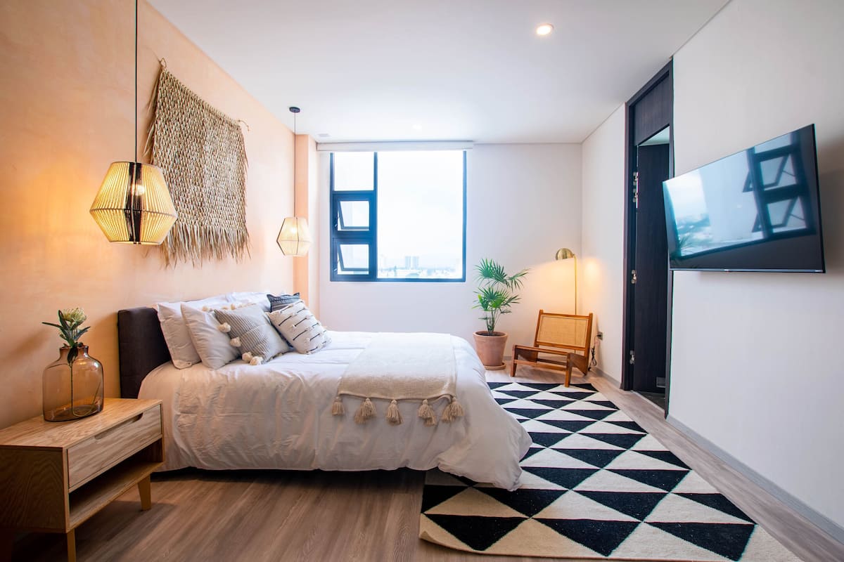 Une chambre moderne avec un lit, une table de chevet, une lampe et une grande fenêtre.