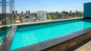 Una piscina en la azotea con vistas a la ciudad, arquitectura moderna y cielos despejados.