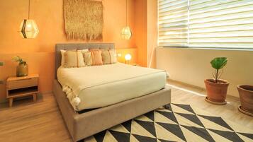 Un dormitorio con cama, mesitas de noche, lámpara, un adorno en la pared y una ventana con persianas.