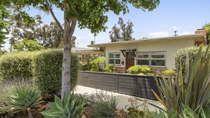 A residential house with a front yard, a wooden fence, and various plants.