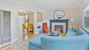 A living room with a fireplace, a sofa, a coffee table, and a dining area with chairs.