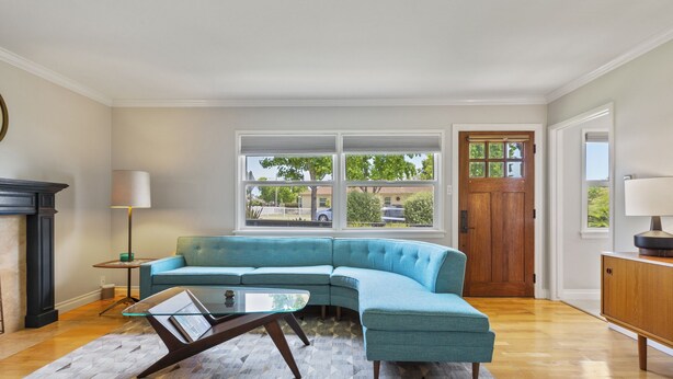 A modern living room with a blue sectional sofa, a glass coffee table, and a patterned rug.