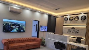 A modern reception area with a sofa, a reception desk, and multiple clocks displaying different time zones. - PARK BUTİK (Ankara)