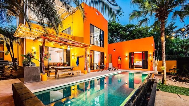 A modern house with a swimming pool, outdoor seating, and a well-lit patio area. - A Tamarindo Sunset (Tamarindo)