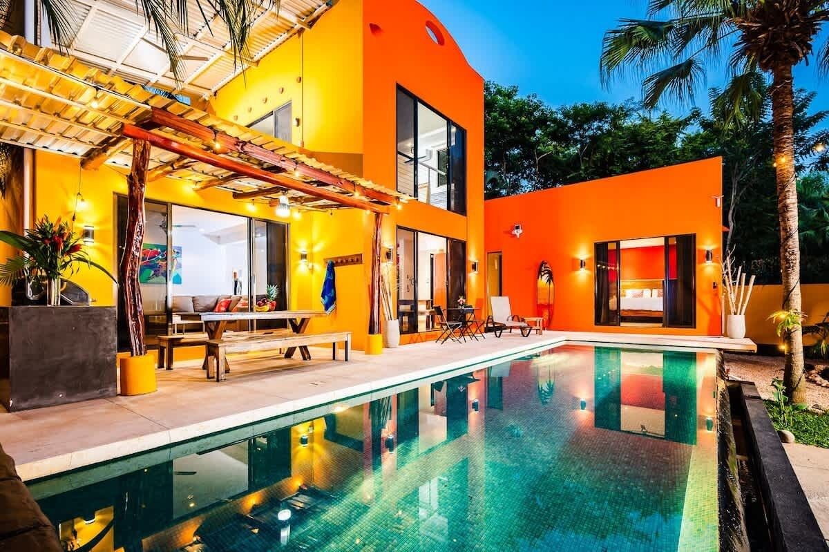 Una casa moderna con piscina, ampie finestre e area relax esterna.