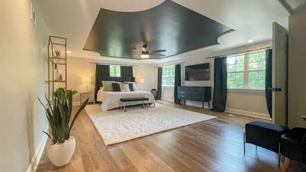 A spacious bedroom with a large bed, a TV, and a seating area with a TV. - Gorgeous home 2mi to LSU - 4 bedroom/3bath (Baton Rouge)