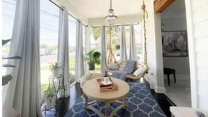 A spacious room with a large window, a hanging chair, a round table, and a potted plant. - Gorgeous home 2mi to LSU - 4 bedroom/3bath (Baton Rouge)