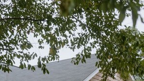 A two-story house with a porch, a front door, and a staircase leading to the entrance. - The Congaree Cottage (Cayce)