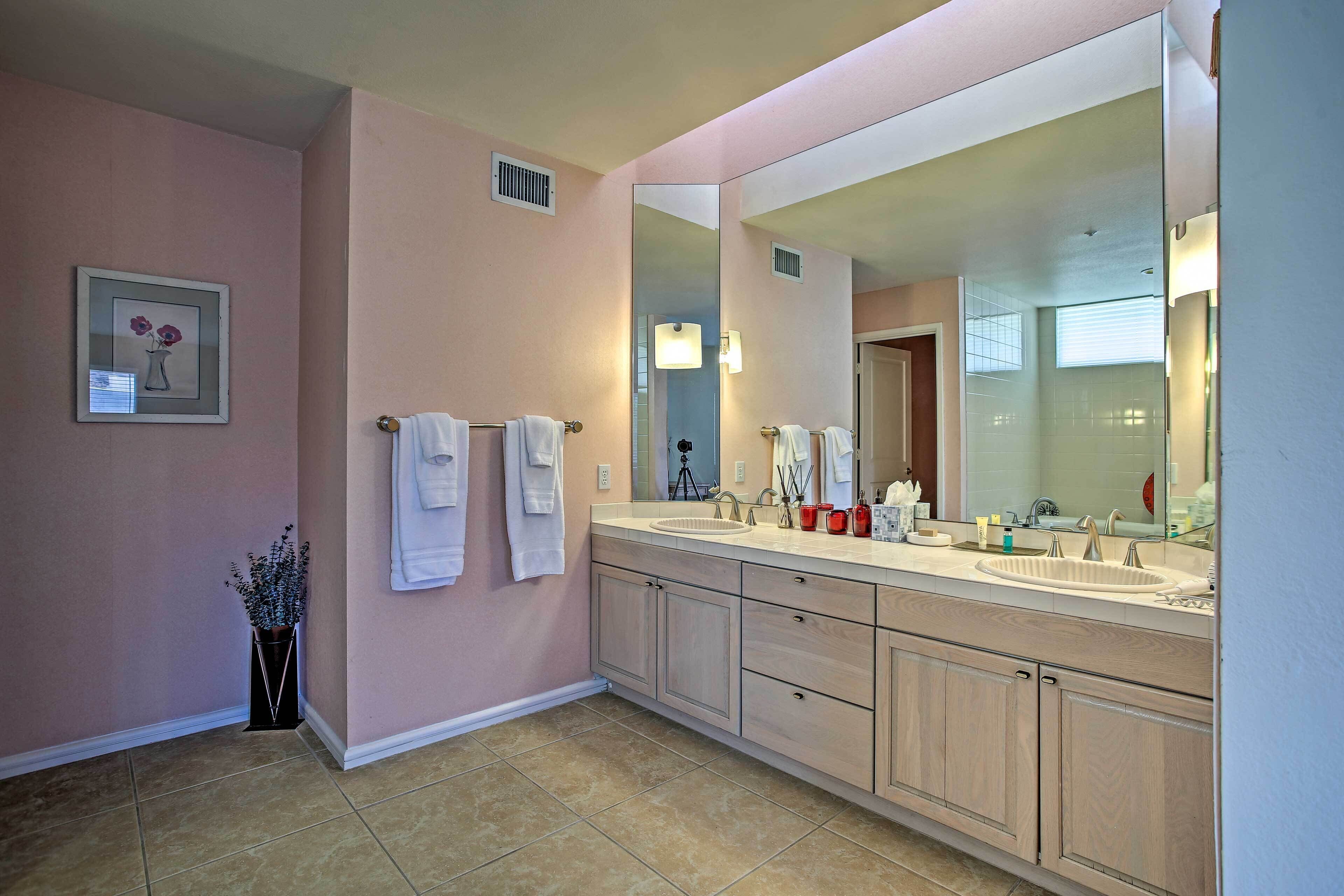 A bathroom with two sinks, a large mirror, and a potted plant.