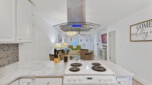 A kitchen with a white stove, a glass hood, and a dining area with a table and chairs.