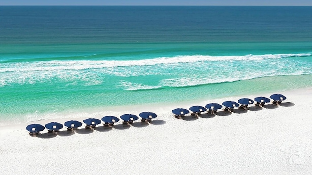 A beach with white sand and a row of blue umbrellas. - BellaVida-Sandestin: Lakefront+Cart to Beach (Miramar Beach)