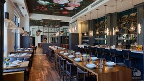 A restaurant with long wooden tables, hanging pendant lights, and a bar area with shelves of bottles. - BellaVida-Sandestin: Lakefront+Cart to Beach (Miramar Beach)