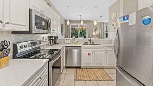 A modern kitchen with stainless steel appliances, white cabinetry, and a central island.