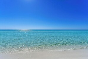 A beach with clear water and a clear sky.