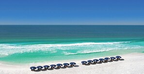A beach with rows of blue umbrellas and white sand.