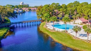 A waterfront property with a swimming pool, a dock, and lush greenery. - CostaLuna-Beachwalk 2BR/2BA/Loft - Cart to Beach! (Miramar Beach)