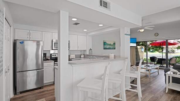 A modern kitchen with white cabinetry, stainless steel appliances, and a central island with seating. - CostaLuna-Beachwalk 2BR/2BA/Loft - Cart to Beach! (Miramar Beach)