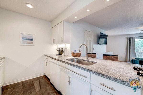 A modern kitchen with white cabinets, granite countertops, and a built-in sink.