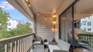 Ein Balkon mit Korbmöbeln, Lichterketten und einem Poster.