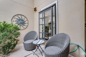 Une terrasse dotée de meubles en osier, d’une porte vitrée et d’un mur décoratif en forme de soleil.