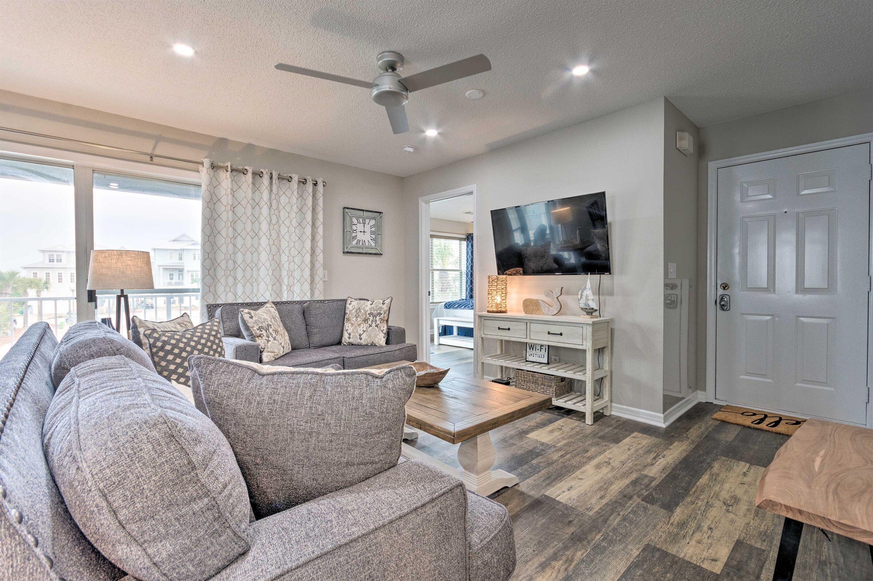 A modern living room with a gray sofa, a coffee table, a TV, and a ceiling fan.
