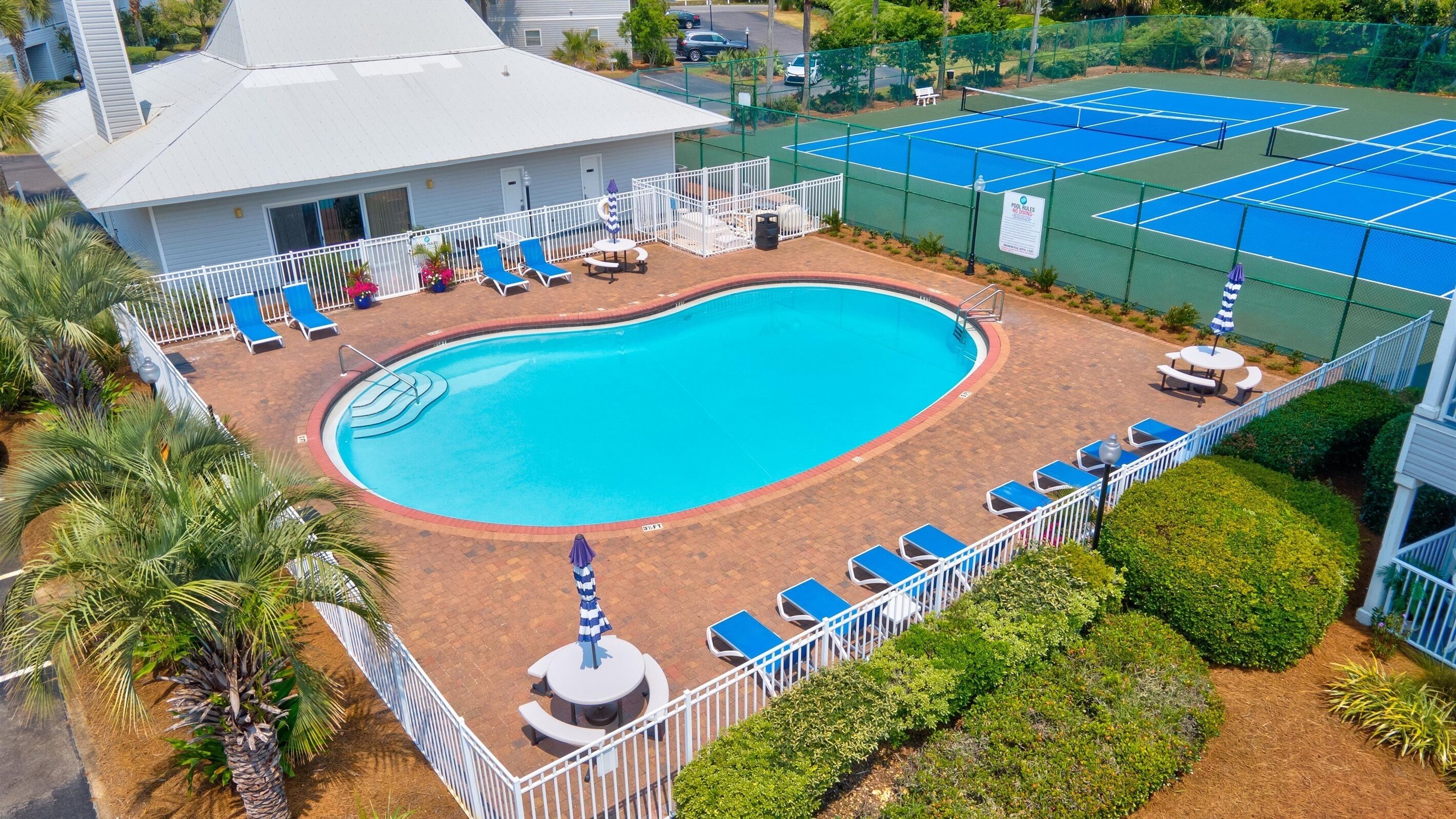 Ein Schwimmbad mit Liegestühlen und einem Tennisplatz.