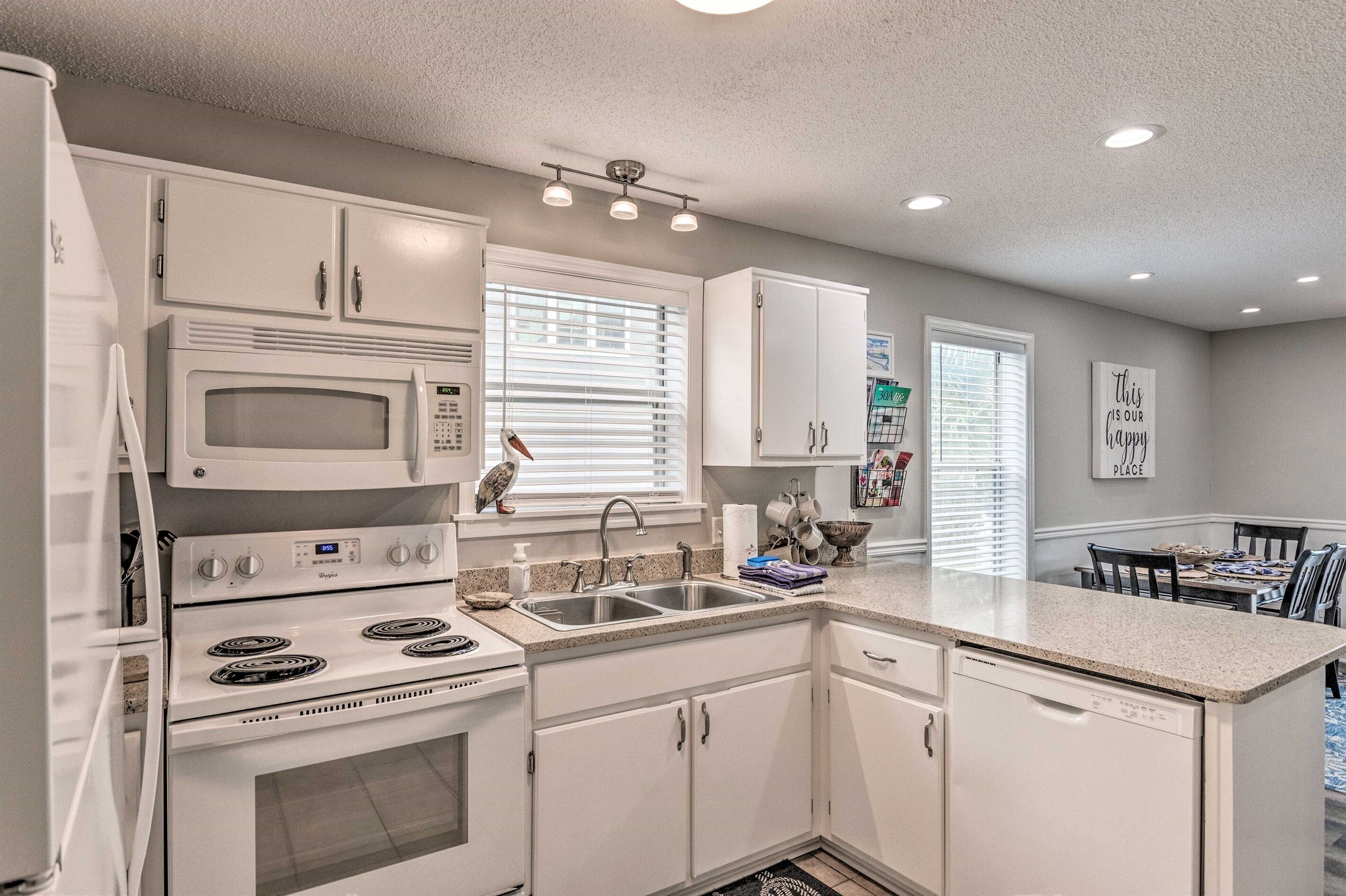 A modern kitchen with white cabinetry, a built-in microwave, a double oven, and a stainless steel sink.