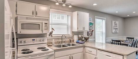 A modern kitchen with white cabinetry, a built-in microwave, a double oven, and a stainless steel sink.