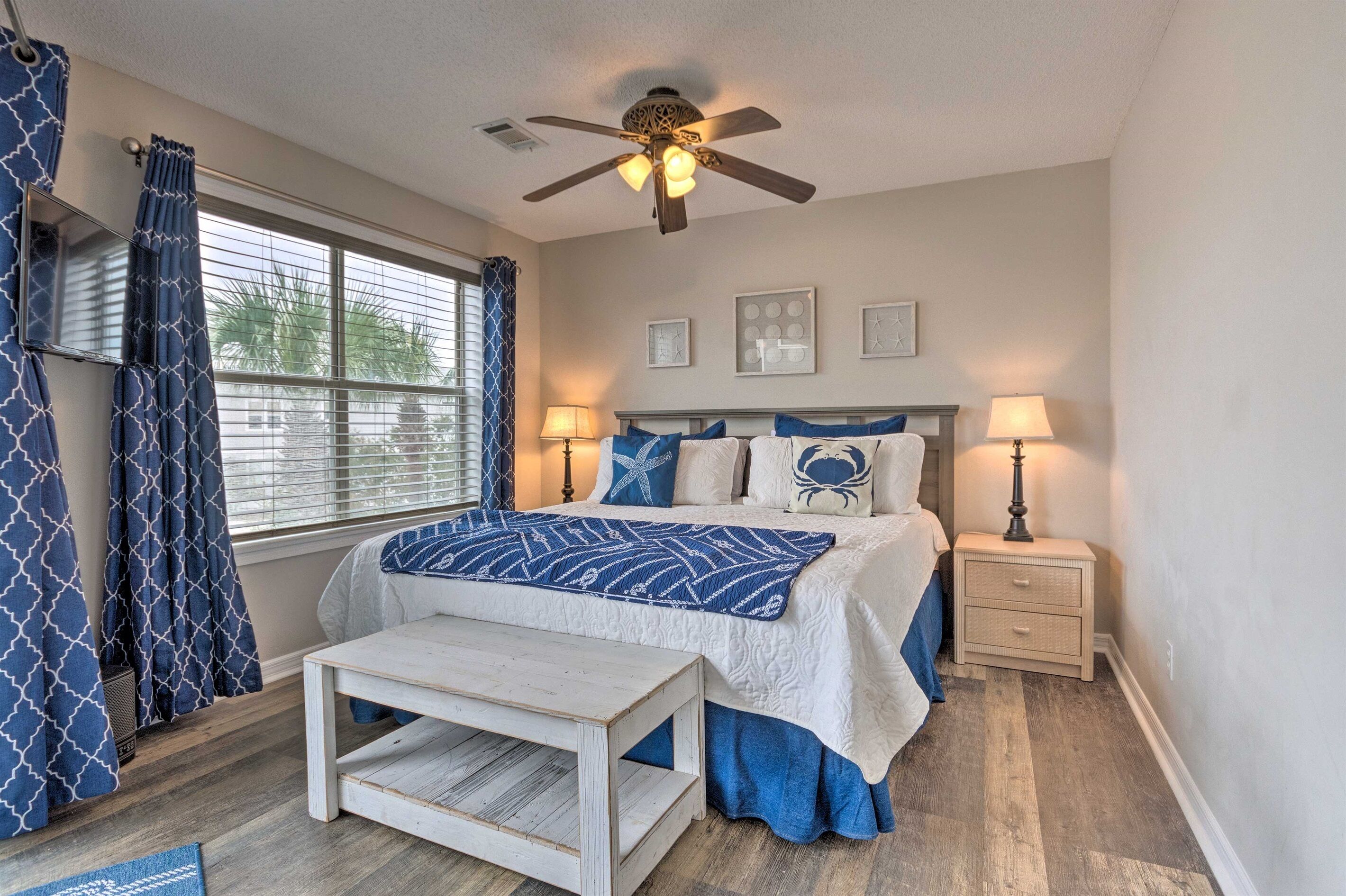 A bedroom with a bed, bedside tables, a ceiling fan, and a window with curtains.