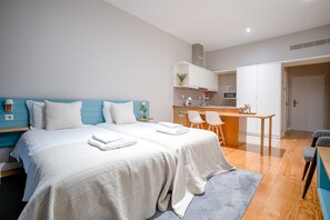 A hotel room with two beds, a kitchenette, and a dining area.