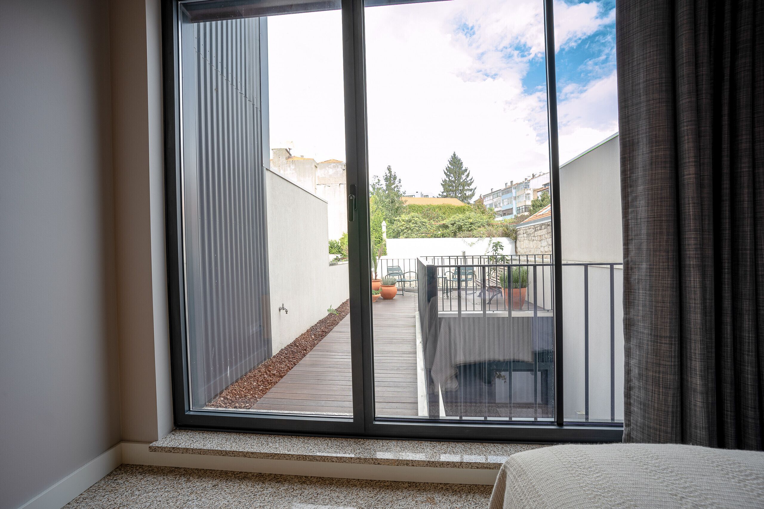 Une pièce dotée d’une grande porte-fenêtre coulissante donnant sur un balcon extérieur avec vue sur le paysage urbain.